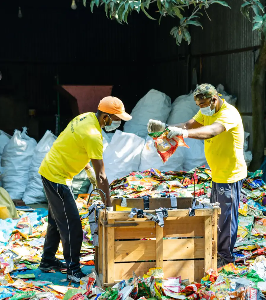 Two Garbageman workers sorting flexible packaging at a material recovery facility